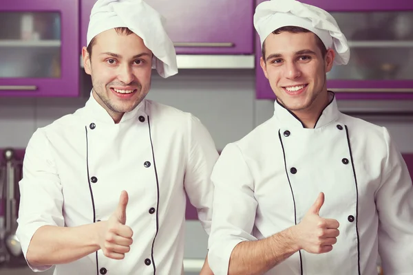 Portrait de deux hommes de travail drôles en uniforme de cuisinier montrant OK sig — Photo