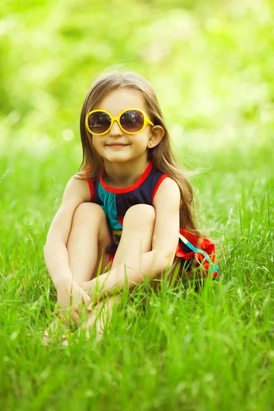 Élégant bébé fille aux cheveux marron clair dans des lunettes de soleil à la mode — Photo