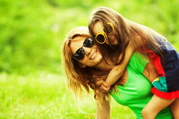 Gelukkige familie plezier. Babymeisje met lange bruin haar en haar mama — Stockfoto