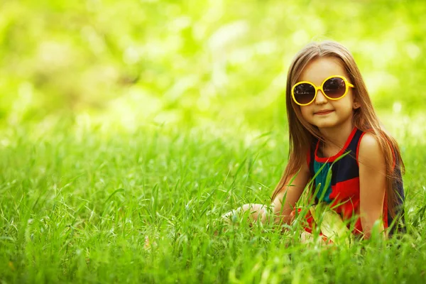Élégant bébé fille avec de longs cheveux brun clair dans des lunettes de soleil à la mode — Photo