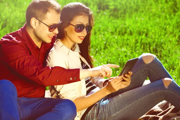 Gadget users concept. Two smiling lovers in trendy clothing and using tablet — Stock Photo, Image