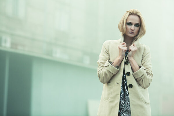 After party concept. Emotive portrait of beautiful blonde in coat