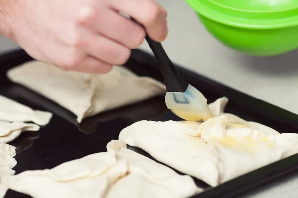 Vegetarian bakery concept. Cook's hands covering wraps of puff pastry with yolk — Stock fotografie