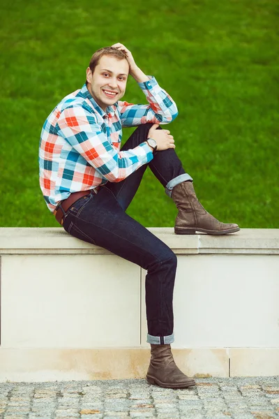 Portrait of happy young happy man relaxing near green lawn — Stock Photo, Image