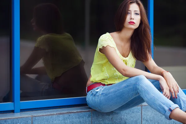 Serious hipster girl in blue jeans in the summer city. — Stock Photo, Image