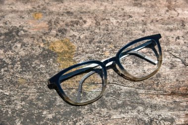 Temiz gözlükler, şeffaf koyu mavi çerçeveli gözlükler. Pis ahşap arka planda klasik tarz.