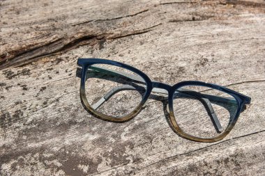 Temiz gözlükler, şeffaf koyu mavi çerçeveli gözlükler. Pis ahşap arka planda klasik tarz.
