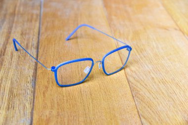 Temiz gözlükler, ahşap arka planda modern tarz tel şeritli mavi çerçeveli gözlükler.