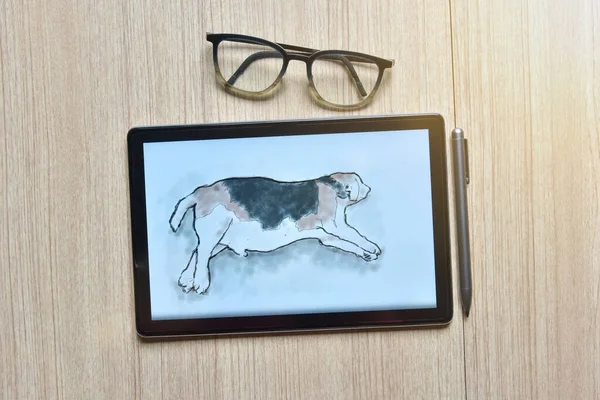 a tablet showing sketch the drawing of beagle dog with digital pens and eyeglasses on wood table, the concept of new technology for drawing and rendering of tablet