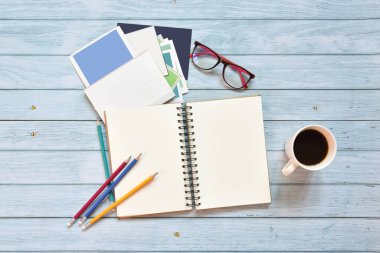 Hayat, gezgin not kavramı, gözlüklü açık defter görüntüsü, kartpostal kahve fincanı ve mavi gökyüzü ahşap arka planında boş sayfaları olan renkli kalem.