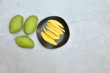 Yeşil mango ve kirli çimento zemin zemin zemininde siyah tabakta yemeye hazır ekşi ekşi ve yüksek vitaminli organik mango grubu fotokopi alanı ile sağlıklı olması için, metin eklemeye hazır.