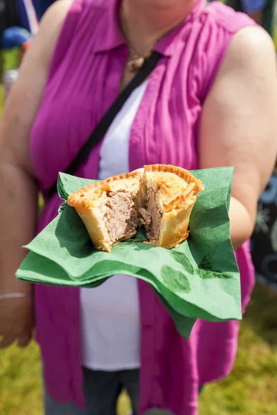 一个年轻的女人伸出在绿色的纸餐巾上的猪肉馅饼 — 图库照片