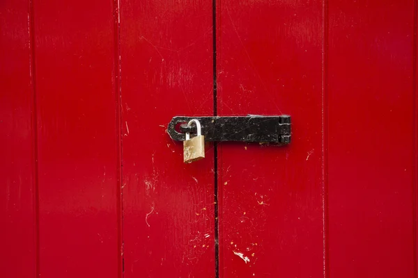 Puerta roja brillante cerrada con candado de latón — Foto de Stock