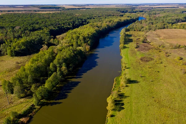 Beautiful scenery on the river, field, forest and sky. Aerial view.