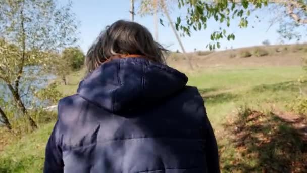 L'uomo adulto cammina verso il fiume lungo una strada di campagna. Vista dal retro. Al rallentatore. Primo piano. — Video Stock