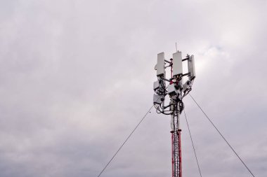 Gri bulutlu arka planda 5G ve 4G hücresel ağ antenli kule.