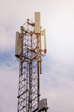 Mavi bulutlu arkaplanda 5G ve 4G hücresel ağ antenli kule.