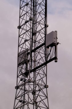 Gri bulutlu arka planda 5G ve 4G hücresel ağ antenine sahip kulenin yakın plan görüntüsü.