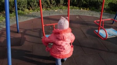 Kız çocuk parkında salıncakta sallanmaya çalışıyor. Yavaş çekim.