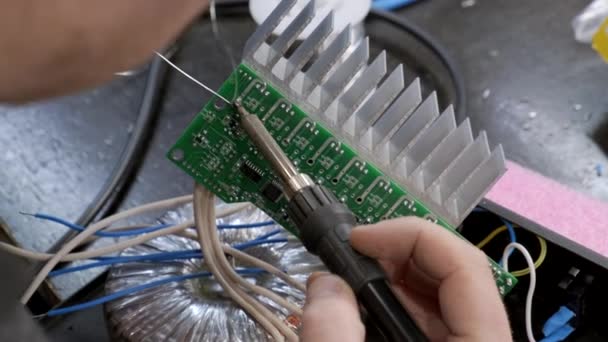 Professionele master die een kabel aan een printplaat en solderen zet. Close-up. — Stockvideo