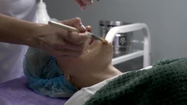 Güzellik uzmanı genç bayana yüz bakımı prosedürü uyguluyor. Yakın plan. Yavaş çekim.