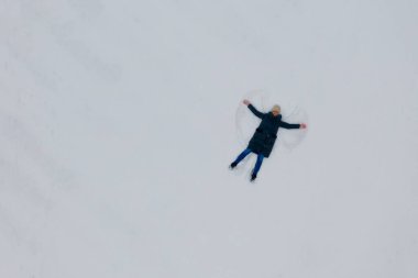 Karda genç bir kadın tarafından yapılmış kar meleğinin havadan görünüşü. Üst görünüm.