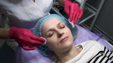 Genç bir kadının yüzünü temizleyen bir güzellik uzmanı. Yavaş çekim.