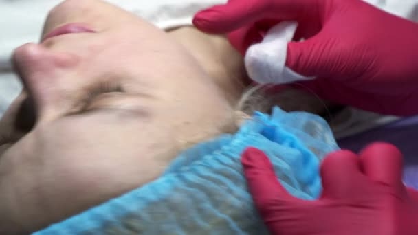 Primer plano de esteticista limpiando cara de mujer joven. Movimiento lento. — Vídeos de Stock