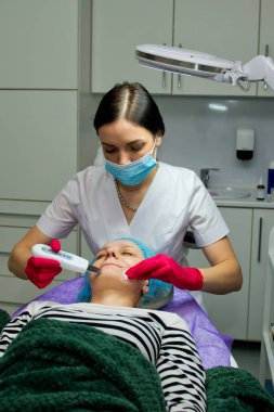 Güzellik salonunda ultrason soyma ve yüz temizleme işlemi yapan genç bir kadın..