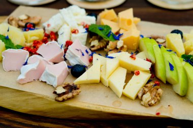 Elma ve fındıklı farklı peynir türleri, bir restoranda, ahşap bir tabakta. Kapat..