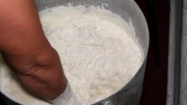 İnsan eli ekmek hamurunu büyük bir kasede yoğuruyor. Kapat..