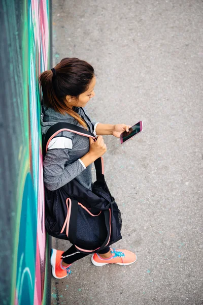 Городская спортивная женщина пишет смс на смартфоне — стоковое фото