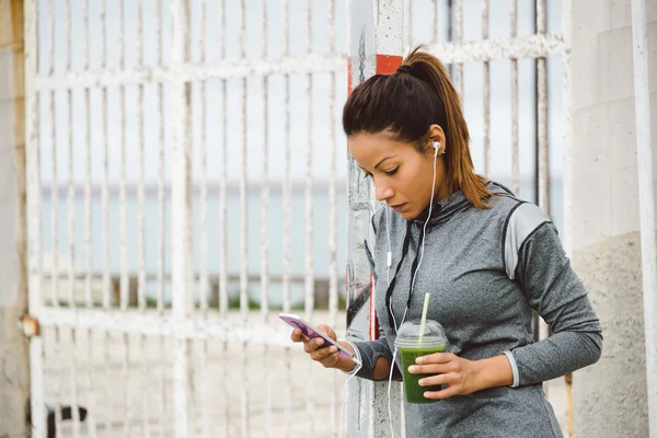 她 smarphone 城市健身女人用发短信 — 图库照片