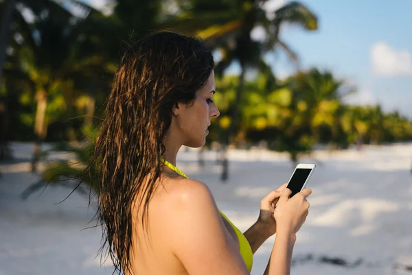 Γυναίκα γραπτών μηνυμάτων στο smartphone σε τροπική παραλία στην Καραϊβική — Φωτογραφία Αρχείου