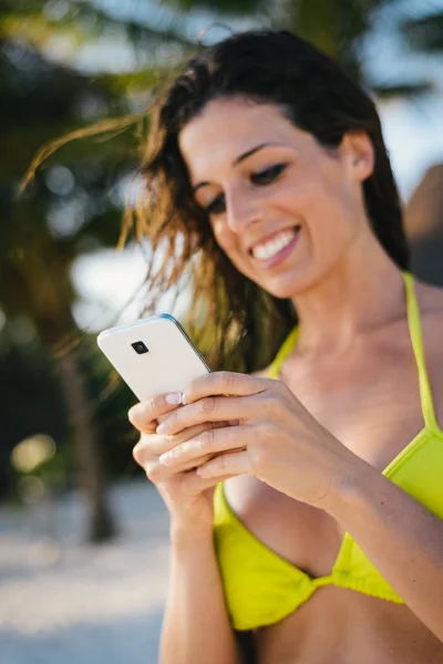 Vrouw texting op smartphone bij de strand — Stockfoto