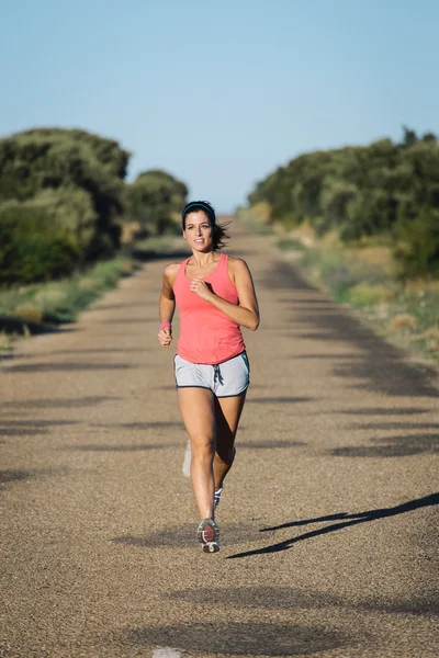 Donna che corre su strada asfaltata di campagna — Foto Stock