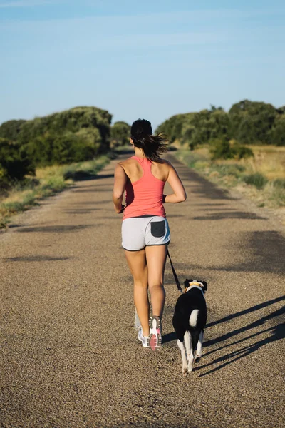 Woman and dog running on country road