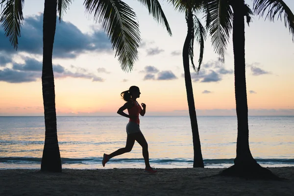 Γυναίκα που τρέχει κατά το σούρουπο σε τροπική παραλία — Φωτογραφία Αρχείου