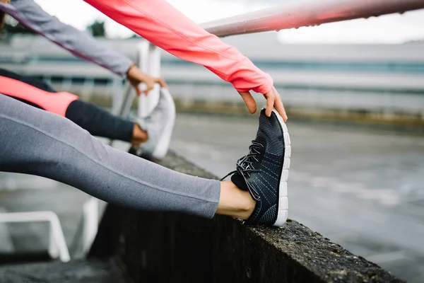 Kvinnliga staden löpare stretching benen — Stockfoto