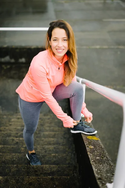 Mujer joven atleta de cordones zapatos deportivos antes de hacer ejercicio —  Fotos de Stock