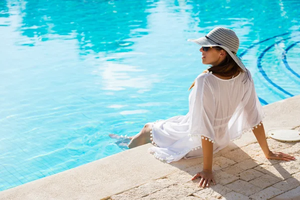 Νεαρή γυναίκα χαλαρώνοντας δίπλα στην πισίνα σε καλοκαιρινές διακοπές — Φωτογραφία Αρχείου