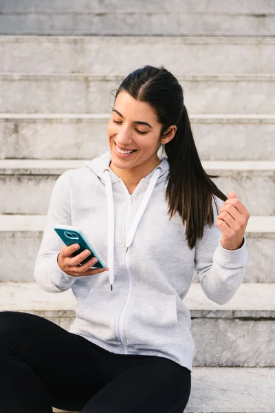 Desportivo jovem mulher mensagens de texto no smartphone — Fotografia de Stock