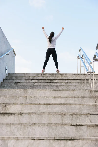 Успешный спортсмен поднимает руки после бега по городской лестнице — стоковое фото