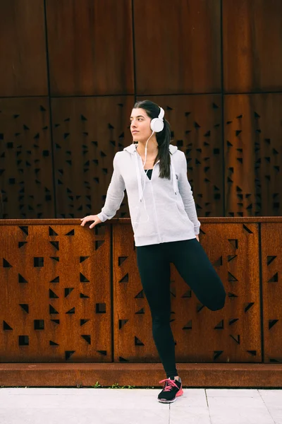 Молодая городская фитнесс-женщина растягивает ноги четырехглавыми — стоковое фото