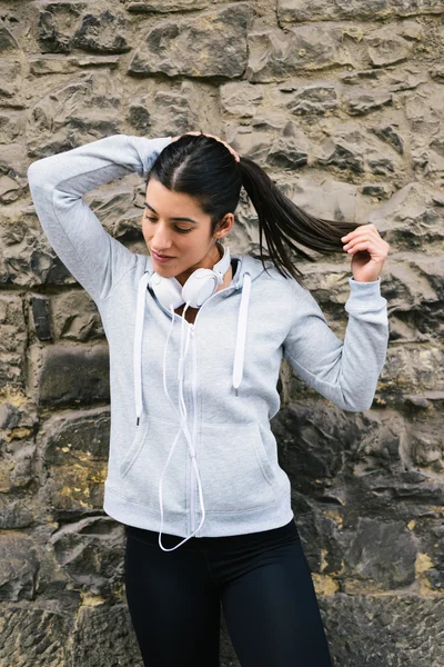 Sporty woman tying ponytail during a workout rest — Stock Photo, Image