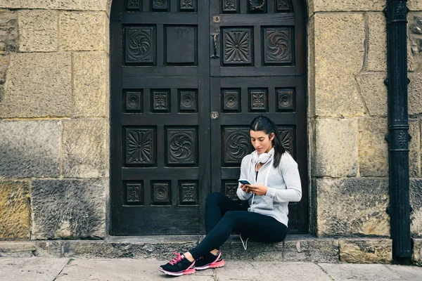 Fitness urban woman rest for texting on smartphone — Stock Photo, Image