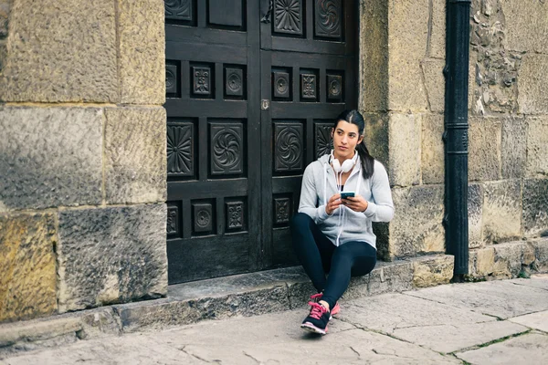 Fitness mujer urbana descanso para mensajes de texto en el teléfono inteligente —  Fotos de Stock