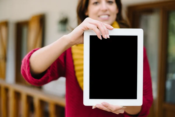 Женщина показывает экран планшета снаружи дома осенью — стоковое фото