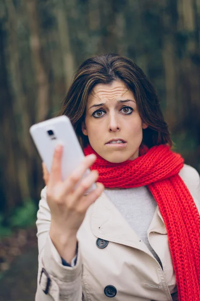 Worried woman with smartphone — Stockfoto