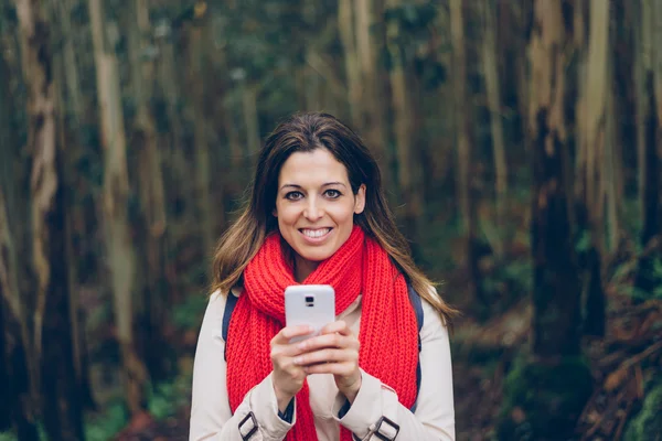 Mujer mensajes de texto en el teléfono inteligente durante un viaje al bosque —  Fotos de Stock